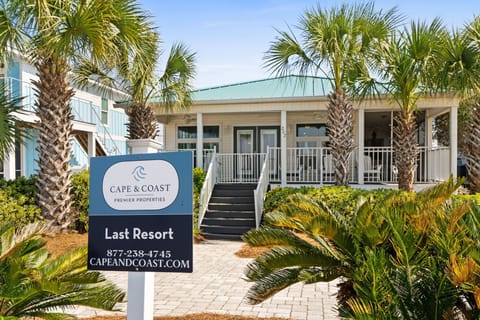 A charming beachside property nestled among swaying palm trees, with a welcoming entrance and tropical landscaping that sets the perfect coastal vacation mood.