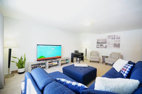 Comfortable living area featuring a large sectional couch, Smart TV, and piano.