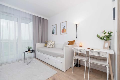 A bright living room with a sofa, a small desk, and a minimalist lamp, creating a cozy workspace.

