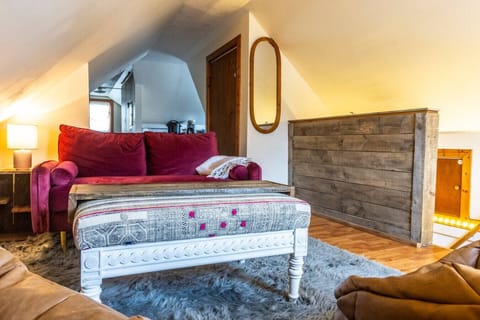 Cozy attic retreat with plush gray shag carpet, a colorful loveseat, and massage-equipped bean bag chairs. Soft lighting and tree-line window views create a warm, relaxing atmosphere. ️✨