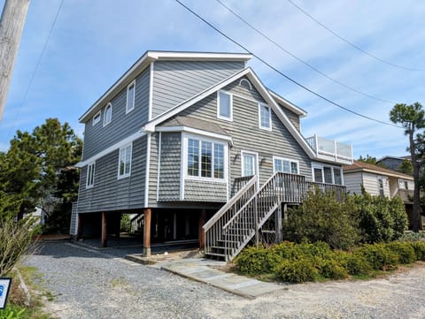 9 South Seventh Street - Property Exterior - Front exterior view of the raised coastal home, showing the staircase entrance, foundation pilings, and surrounding landscaping.