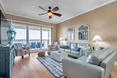 Sun-filled living room w/ comfortable seating, soft textures, & sliding doors to the balcony.