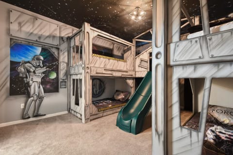 Space-themed kids' bedroom with bunk beds, slide, galaxy murals, and cosmic vibes.