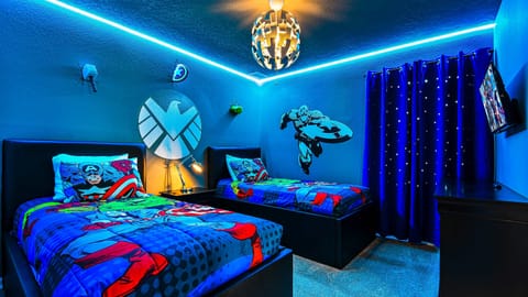 Superhero-themed bedroom with vibrant lighting, custom decor, and twin beds.