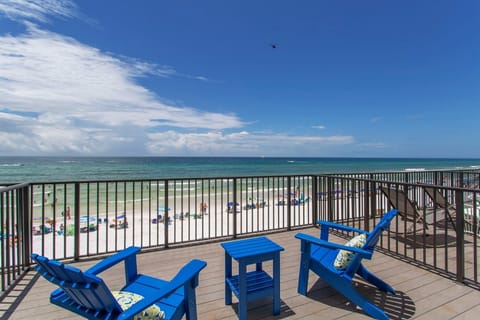 Stunning beachfront balcony with vibrant blue chairs overlooking pristine white sand and turquoise waters.
