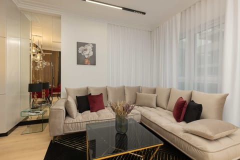 A modern living room with a beige sectional sofa, large windows, and elegant decor.
