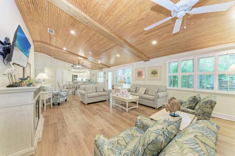 Relax in your spacious living room featuring warm wood ceilings, comfortable seating, and abundant natural light from oversized windows.