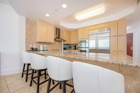 Modern kitchen featuring stainless appliances, granite countertops, Keurig and coffee maker, and stylish bar seating