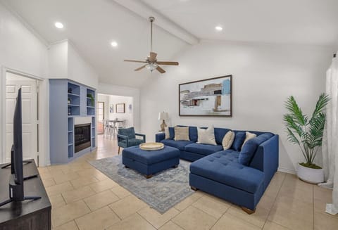 Gather in this bright and spacious living area, where vaulted ceilings and natural light create an open, airy feel. A plush sectional invites you to stretch out and relax, while the cozy fireplace and modern décor add warmth and charm. Perfect for movie n