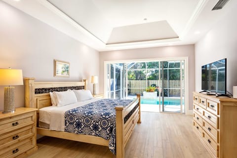 Master bedroom with king bed, tv and entrance to the pool