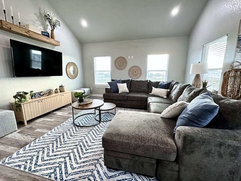 Bright and cozy living room with a large gray sectional, blue and white rug, and natural decorative touches.
