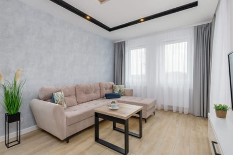 A modern living room with a light sofa, coffee table, and a bright window.
