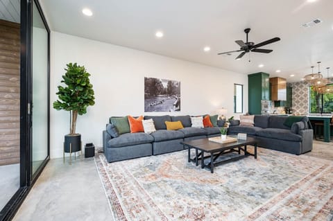 Large living room with oversized sectional couch, balcony and Comal River views