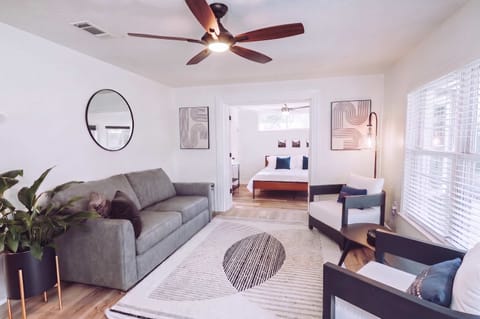 Relax in a bright, thoughtfully curated living area featuring designer touches, lush greenery, and a seamless transition into the primary suite. Perfect for those who appreciate clean lines and a peaceful atmosphere.