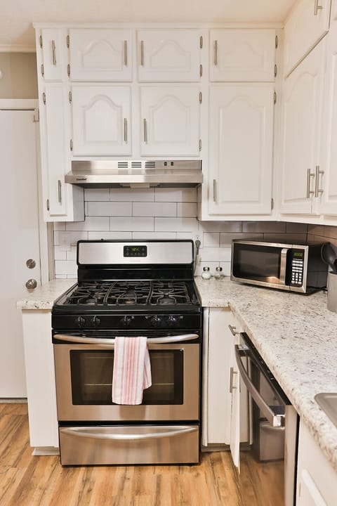 Large and well stocked kitchen with a gas stainless steel stove.