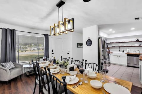 Beautifully handmade farmhouse dining table (sits 8 people), stylish farmhouse lighting, comfy sitting nook for 2 people with small game / reading table with open concept kitchen in background.