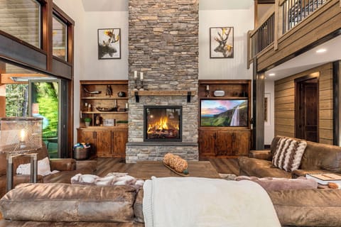Double-Height Stone Gas Fireplace With Built-Ins, Leather Sofas And Grand Lodge Aesthetic