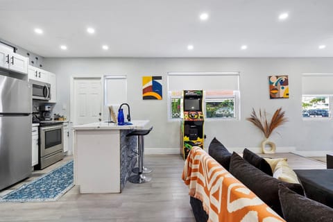 Open-concept living room with a fully stocked kitchen and gaming arcade.