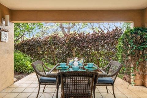 A cozy garden-view lanai with a two‑seat dining set, perfect for enjoying relaxing outdoor meals surrounded by lush tropical greenery.