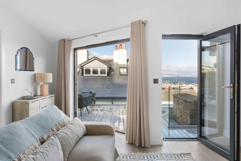 Seating area with doors opening to decking with sea view - The Sail Loft Suite