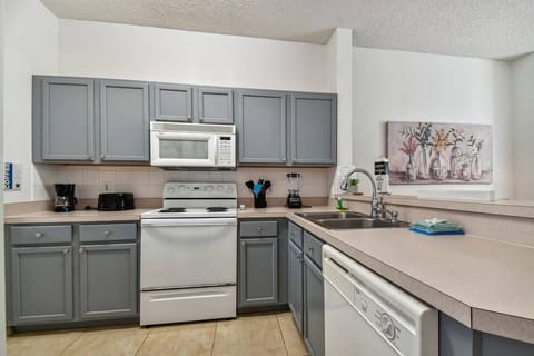 Discover a well-equipped kitchen with stylish gray cabinets and a bright countertop to inspire your culinary creativity. Enjoy modern appliances, including a microwave and dishwasher, all enhanced by charming decor that adds.