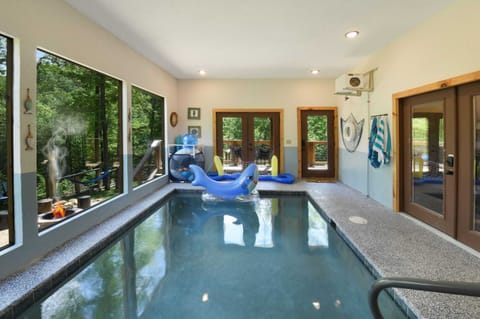 Indoor pool area with large windows overlooking the forest and playful inflatable toys.