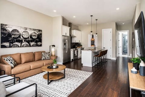Cozy, bright lounge with wooden floors and comfortable white and brown seats.