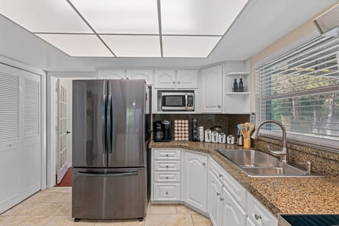A kitchen that exudes timeless elegance! You'll be captivated by the crisp, clean lines of the white painted cabinets that provide a stunning contrast against rich, natural wood flooring.
