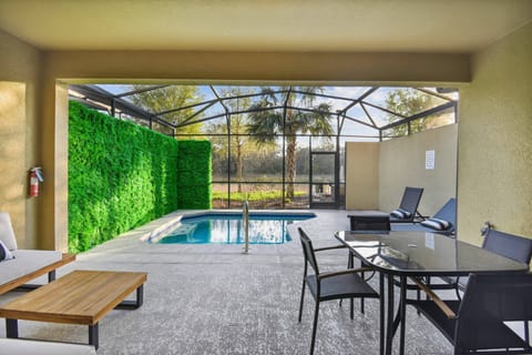 Discover a sunlit oasis with a modern private pool and lush green accents. Unwind on chic lounge chairs or gather at the elegant dining table, all while enjoying expansive views of nature around you.