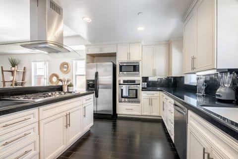 White wooden modern kitchen with stainless steel appliances and a huge island w/gas range stove