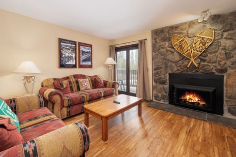 Cozy up by your crackling stone fireplace in this warm living room, where rustic charm meets comfort after mountain adventures.