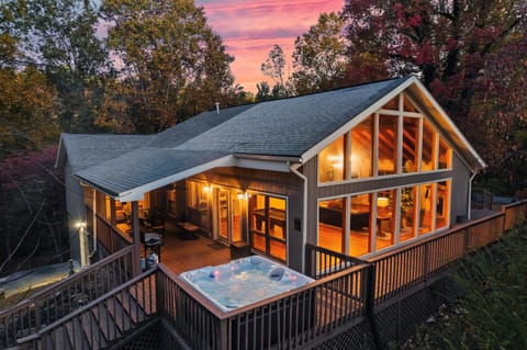Your private Smoky Mountain escape; cozy lights glowing from a chalet nestled among the trees with a wraparound deck to unwind.