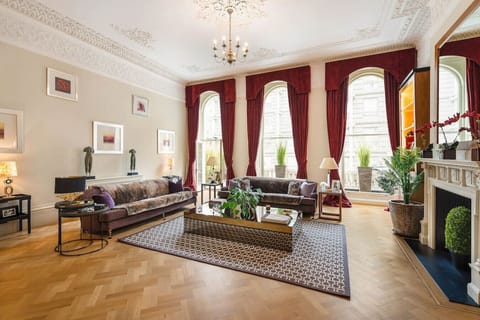 Grand Living Room | High Ceilings | Open Plan Space | Hardwood Flooring | Artwork | Decorative Fireplace | Bespoke Cabinetry | Wooden Shutters | Ceiling Lights | Lamps | Large Coffee Table | Large Smart TV with Netflix and Amazon Prime