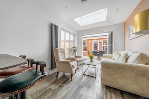 Bright living room with sofa bed, table, smart TV, and 2 arm chairs. 
