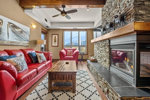 Living room with a gas-lit fireplace, TV, cozy seating options and walkout access to the second-floor balcony.