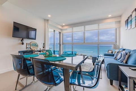 Enjoy breathtaking ocean views from your bright, modern dining space. The turquoise accents mirror the sea beyond your windows, creating a serene coastal retreat.