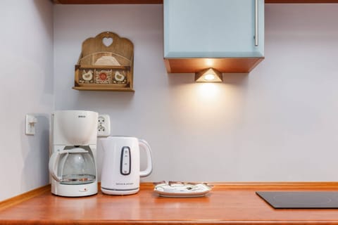 A compact kitchenette with a coffee maker, kettle, and a cozy wooden countertop.