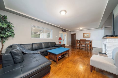 Entry into living room, with leather sectional, gas fireplace, and large smart TV with sound system