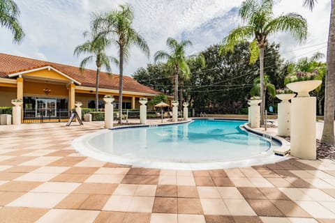 Step into a sun-soaked outdoor oasis featuring a pristine pool surrounded by elegant tiled decking and lush palm trees. The inviting ambiance invites you to relax, unwind, and soak in the tranquility of your surroundings.