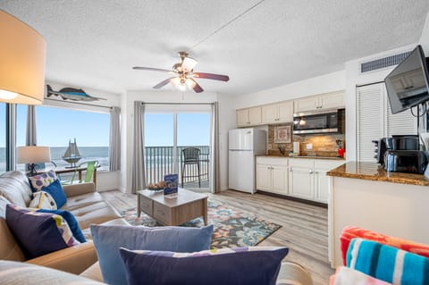 Gulf-front condo living room with ocean-view balcony, open kitchen, and coastal décor at Belleair Beach Club