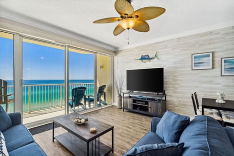Living room offers ample, comfortable seating with flat screen television, gulf views, and a door leading to the unit's private balcony.