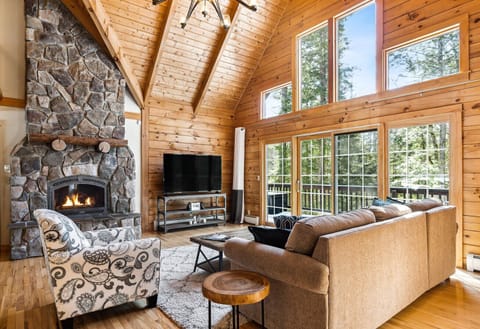 Great room with cathedral ceilings, stone
    fireplace, and floor-to-ceiling windows
    opening to the wraparound deck