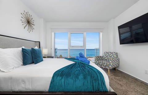 Wake up to endless ocean views right from your bed. Crisp white linens, plush teal accents, and floor-to-ceiling windows invite the sea into your personal sanctuary.