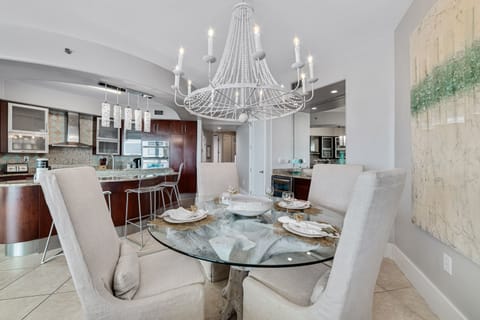 The dining table is set for four with additional seating at the kitchen bar