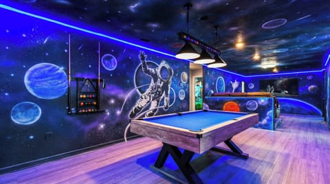 Stunning space-themed game room with billiards, neon lights, and cosmic wall art.