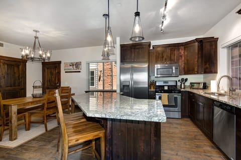 This modern kitchen features stainless steel gas appliances, rich wood cabinetry, and a granite island with bar seating. Perfect for home-cooked meals, it combines functionality and style for a seamless cooking and dining experience.