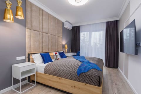 A stylish bedroom with a wooden bed frame, cozy bedding, and soft lighting for a warm ambiance.
