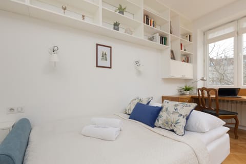 A cozy living area with a blue sofa, a white table, and a built-in shelving unit for decor and storage.
