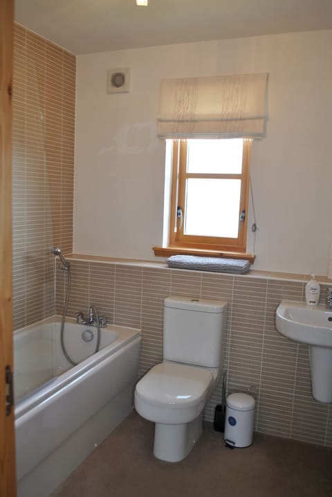 The modern family bathroom has a full size bath with shower overhead