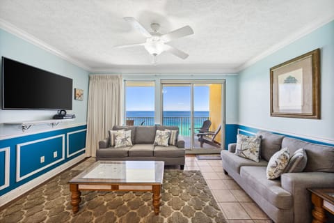 Bright living room w/ comfy seating, a wall-mounted TV & balcony access overlooking the water